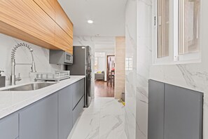 A modern kitchen with grey cabinets, a stainless steel sink, and a built-in microwave. - Spacious Flat with 2 Bedrooms in CDMX (Mexico City)