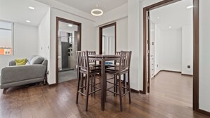 A modern dining area with a wooden table and chairs, a grey sofa, and a wooden floor. - Spacious Flat with 2 Bedrooms in CDMX (Mexico City)