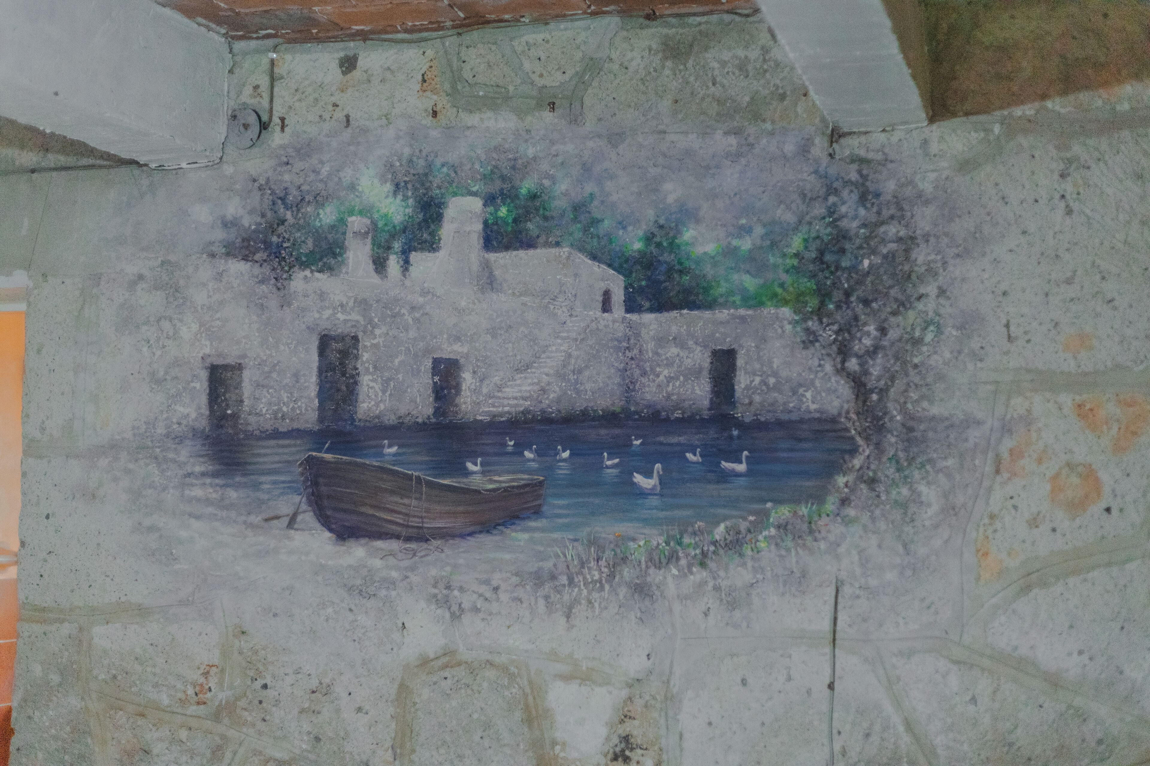 A mural of a boat on water with buildings in the background.