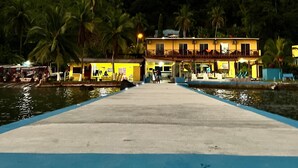 A waterfront hotel with a long, narrow pool in the foreground. - ScubaPortobelo (Portobelo)