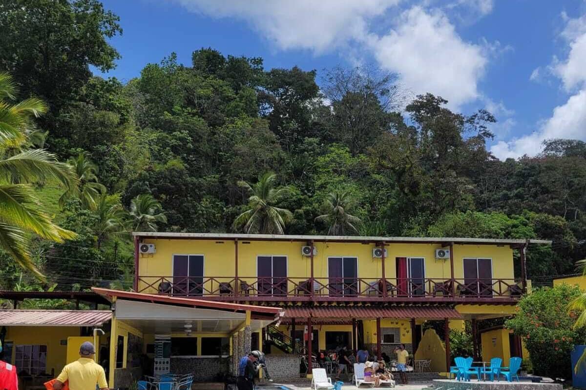 A yellow building with a balcony, a swimming pool, and outdoor seating.