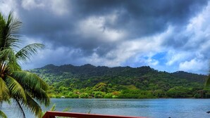 A view from a red metal railing overlooking a lake, with lush greenery and a mountain in the background. - ScubaPortobelo (Portobelo)