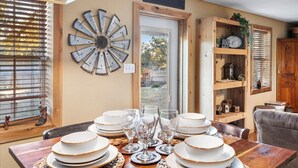 A dining area with a wooden table set for a meal, surrounded by chairs. - Charming Barndominium with Farm Animals – Just 5 Minutes from Lake Georgetown (Georgetown)