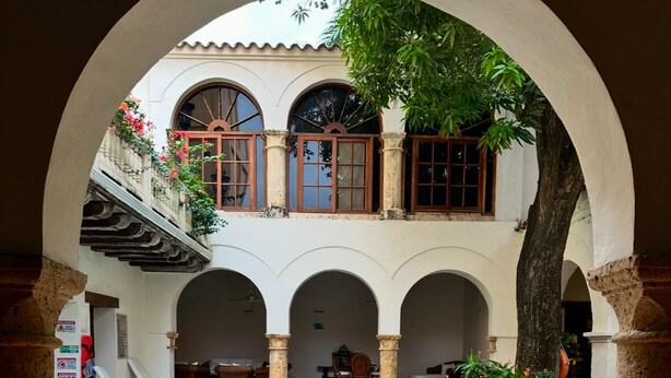 A courtyard with a pool, arches, and a staircase leading to a balcony. - Apartment in the Historic Center of Cartagena (Cartagena de Indias)