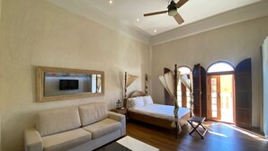 A spacious room with a large bed, a sofa, a television mounted on the wall, and a ceiling fan. - Apartment in the Historic Center of Cartagena (Cartagena de Indias)