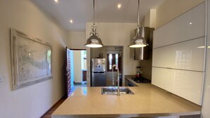 A modern kitchen with a central island, pendant lights, stainless steel appliances, and a view into the dining area. - Apartment in the Historic Center of Cartagena (Cartagena de Indias)