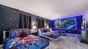 A Star Wars-themed bedroom with two beds, star-patterned walls, and a large mural.