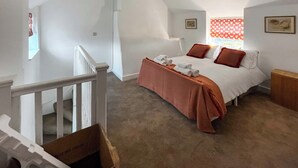 A bedroom with a bed, a window with a view, a staircase, and a ceiling light. - Ddwylig Bach - UK48623 (Rhyl and Prestatyn)