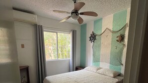 A bedroom with a bed, a ceiling fan, a window, and a door. - Raya apartment  (Ixtapa Zihuatanejo)