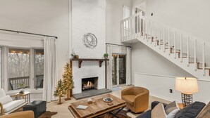 Amplia sala de estar con chimenea, escalera y un rincón de asientos acogedor.