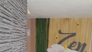 En vägg med ett stenmönster som ger en känsla av struktur, en väggmålning med ett blommönster och ordet ”Zen”, och en träpanel med ett bambumotiv.