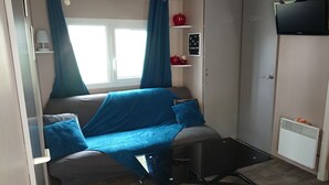 Ett kompakt vardagsrum med en soffa, ett litet bord och en tv som är monterad på väggen.