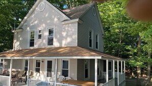 A two-story house with a porch, wooden deck, and a small garden area. - Angola on the Lake Beach Front House  4BR  private beach wrap-around porches (Angola)