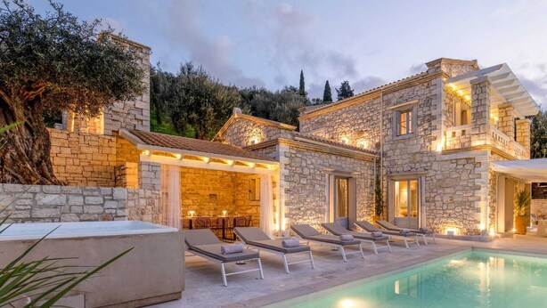 A stone villa with a swimming pool, outdoor seating, and a well-lit patio area. - Ionian Stone Luxury Villa Aether (Corfu)