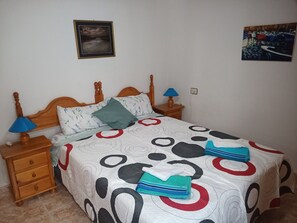 Cozy bedroom with a wooden bed, two bedside tables, and a nightstand, each with a lamp.