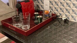 A kitchen counter with a red tray holding glasses and a coffee maker.