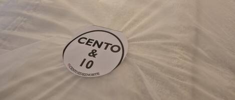 A bed with a white comforter and a circular sticker on the bedspread.