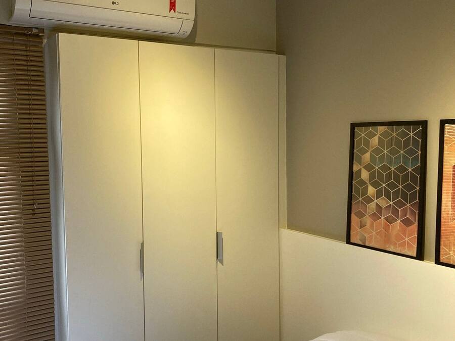 Een slaapkamer met een bed, een kledingkast en een airconditioning.