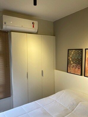 Une chambre à coucher comprenant un lit, une armoire et un appareil de climatisation.
