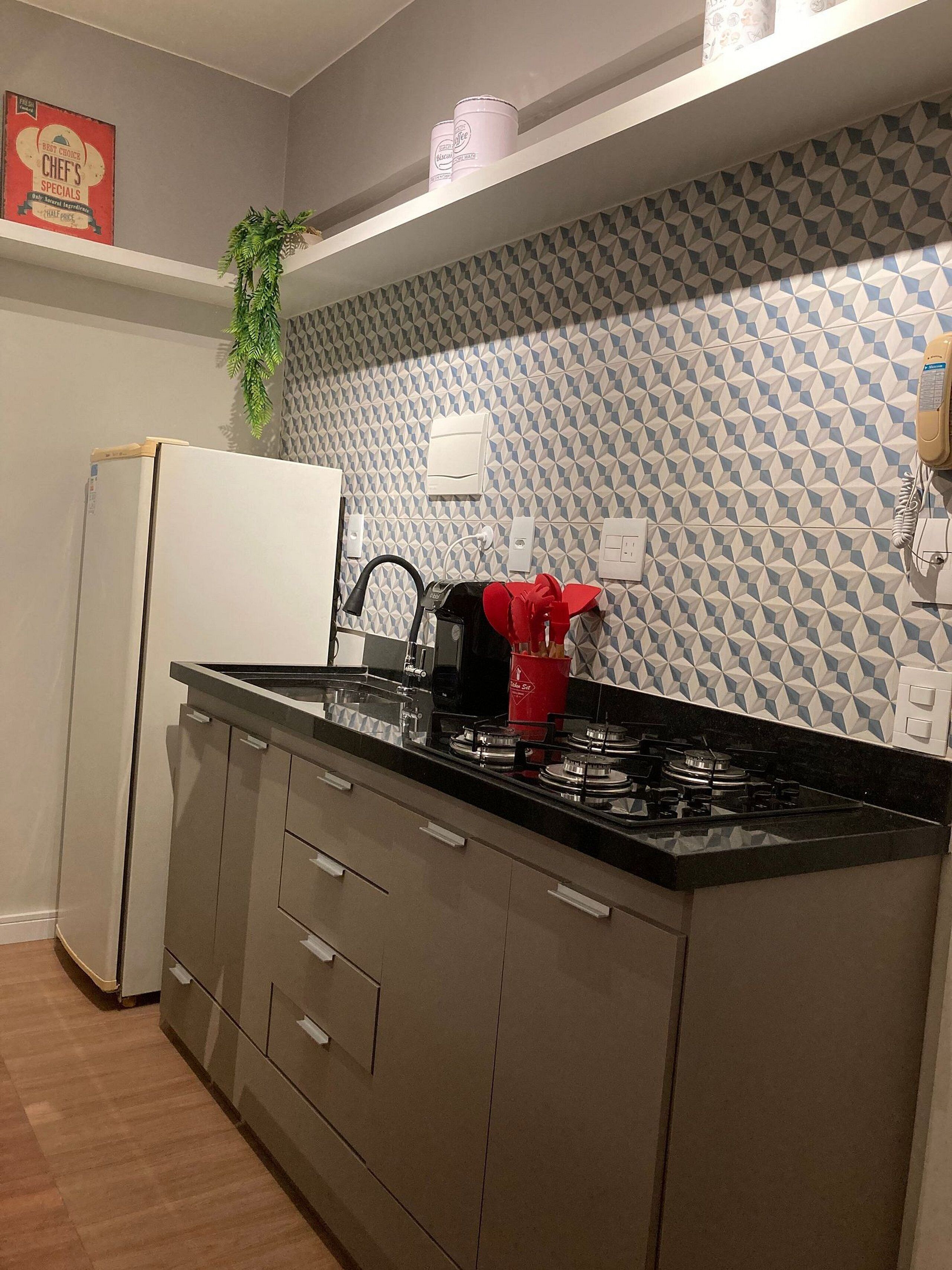 A modern kitchen with a refrigerator, stove, and a patterned backsplash.