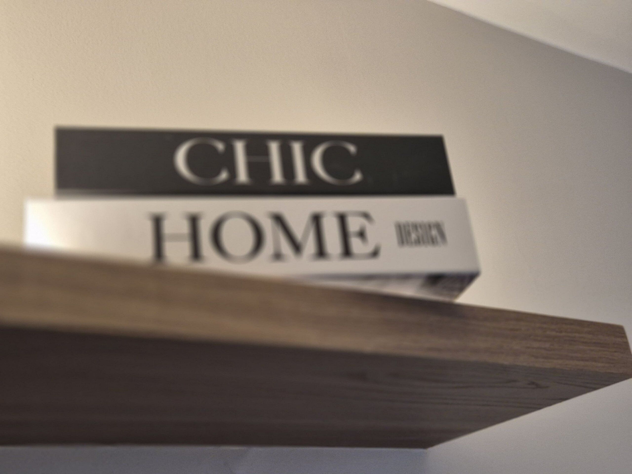Un libro con el título "CHIC HOME" sobre una estantería de madera.