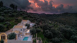 A stone villa with a swimming pool, surrounded by dense vegetation and hills. - Ionian Stone Luxury Villas in Corfu - Estate (Corfu)