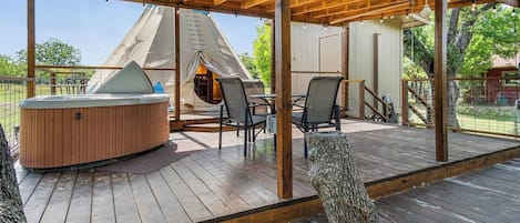 Eine Holzterrasse mit Whirlpool, Stühlen und einer Zelthütte.