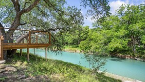 A wooden bridge over a river, surrounded by lush greenery and trees. - Bandera Stronghold Retreat (Bandera)