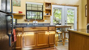 A kitchen with wooden cabinets, a granite countertop, a sink, and a window overlooking greenery. - Bandera Stronghold Retreat (Bandera)