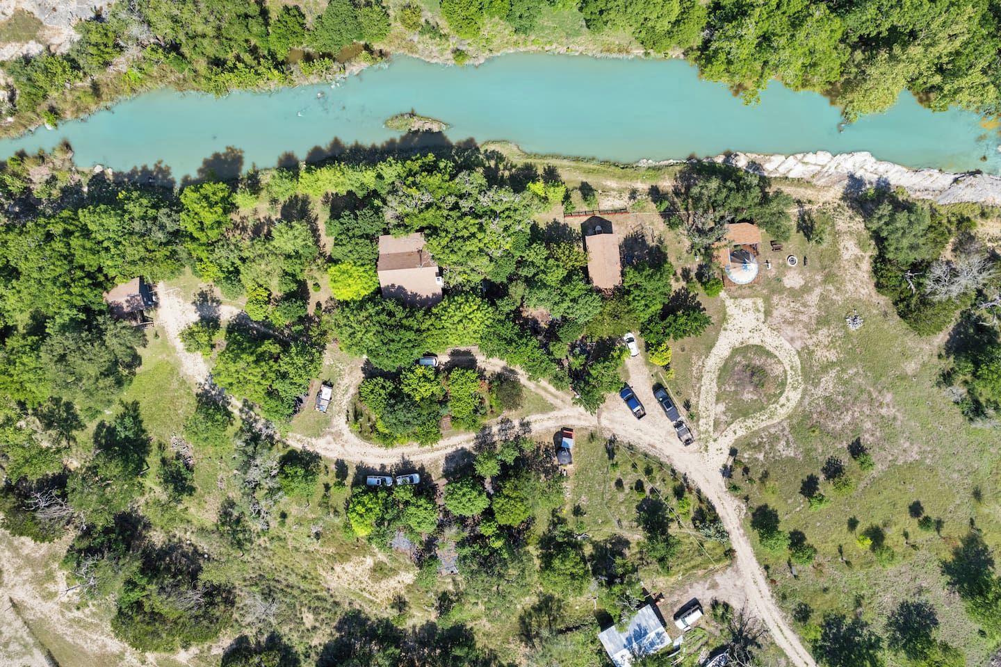 Vista aérea de una propiedad con un lago, varios edificios y un camino sinuoso.