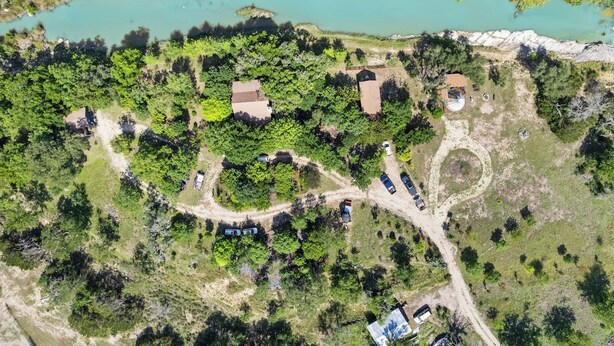 Eine Vogelperspektive auf ein Anwesen mit einem See, mehreren Gebäuden und einer kurvenreichen Straße.