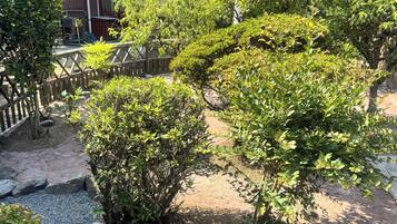 A traditional Japanese garden with a gravel path, rocks, and neatly trimmed bushes.