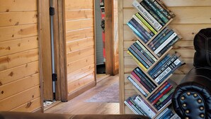 A wooden interior with a bookshelf filled with books, a leather couch, and a wooden door. - Sauna• Hot tub• 2 King Beds• Game Room• Mtn views• Close to Breck• Pet friendly (Fairplay)