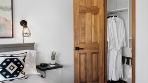 A hotel room with a wooden door, a bedside table with a lamp, a white pillow, a small cactus, and a robe hanging on a rack. - Sauna• Hot tub• 2 King Beds• Game Room• Mtn views• Close to Breck• Pet friendly (Fairplay)