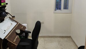 Ein kleiner Büroraum mit Schreibtisch, Stuhl, Klimaanlage und einem Fenster.