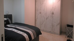 Ein Schlafzimmer mit einem Bett, einem Kleiderschrank und einem kleinen Tisch mit einer Lampe.