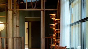 A wooden interior with a green chair, a small table, and a staircase. - Ned's Bright - Total Luxury (Bright)