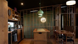 A modern kitchen with wooden cabinetry, a central island, and a dining area with a wooden table and chairs. - Ned's Bright - Total Luxury (Bright)
