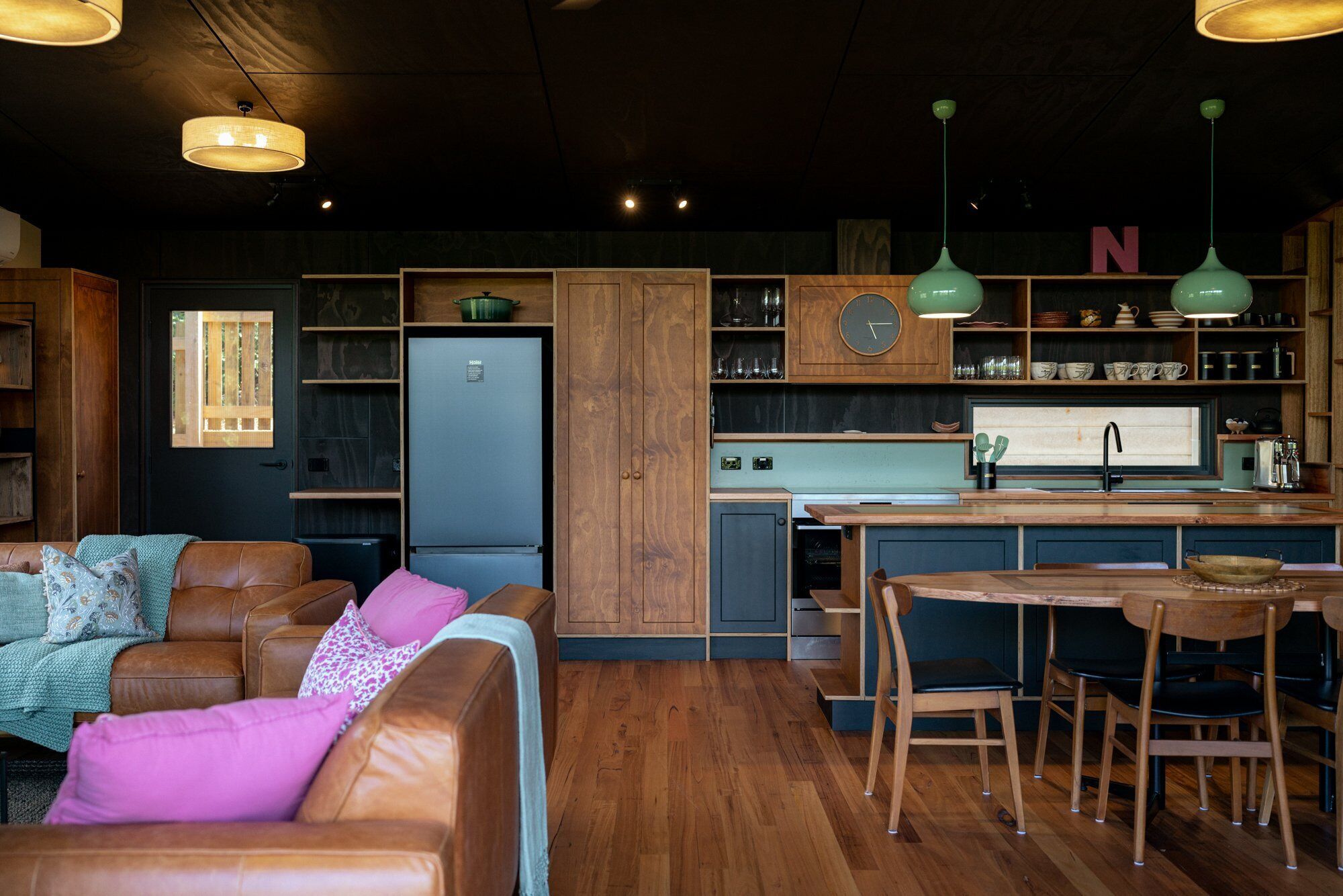 A compact kitchen with wooden cabinets, a built-in fridge, and a bar area.