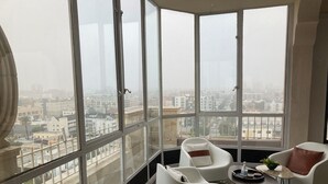 A high-rise apartment with a large panoramic window, white furniture, and a small round table with a tray. -  1-bedroom condo in Long Beach with 2 private patios.  (Long Beach)