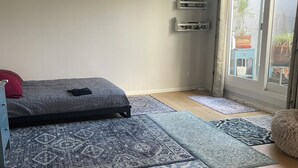 A room with a bed, a small table, and a sliding glass door leading to a balcony. -  1-bedroom condo in Long Beach with 2 private patios.  (Long Beach)
