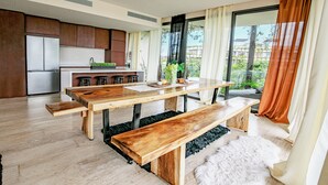 A modern kitchen with wooden cabinets, a stainless steel refrigerator, and a dining area with a wooden table and benches. - Chic 2-bedroom penthouse with private pool, gym, WiFi, W/D & Concierge (Tulum)