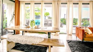 A modern living room with a wooden dining table, a bench, and a sofa. - Chic 2-bedroom penthouse with private pool, gym, WiFi, W/D & Concierge (Tulum)