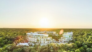 A modern, circular building complex surrounded by dense greenery, with a clear view of the horizon. - Chic 2-bedroom penthouse with private pool, gym, WiFi, W/D & Concierge (Tulum)