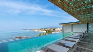 Una piscina infinita con agua azul cristalina que domina una playa y el océano.