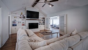 A spacious living room with a large sectional sofa, a fireplace, and a ceiling fan. - The Game Palace @ Sugar Magnolia (Jackson)