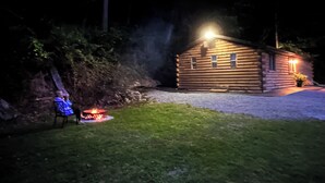 Hirsimökki, jossa on ulkona nuotiopaikka ja tuoli.