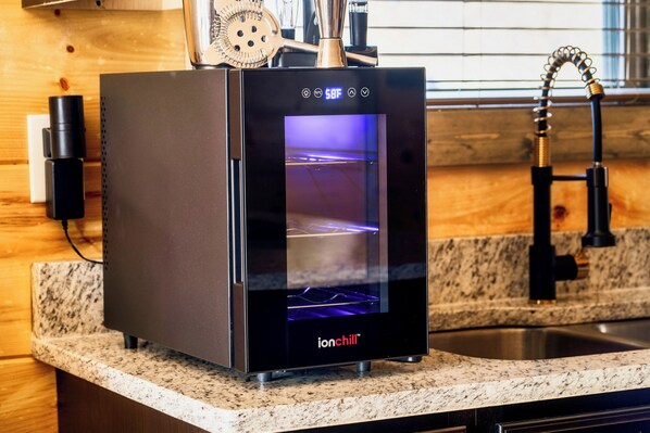 Una cocina con encimera, lavamanos y un electrodoméstico moderno con pantalla digital.
