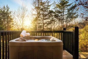A hot tub on a wooden deck with a forest view.