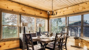 Ein Esszimmer aus Holz mit einem für vier Personen gedeckten Tisch, großen Fenstern und einer Kristallleuchter.